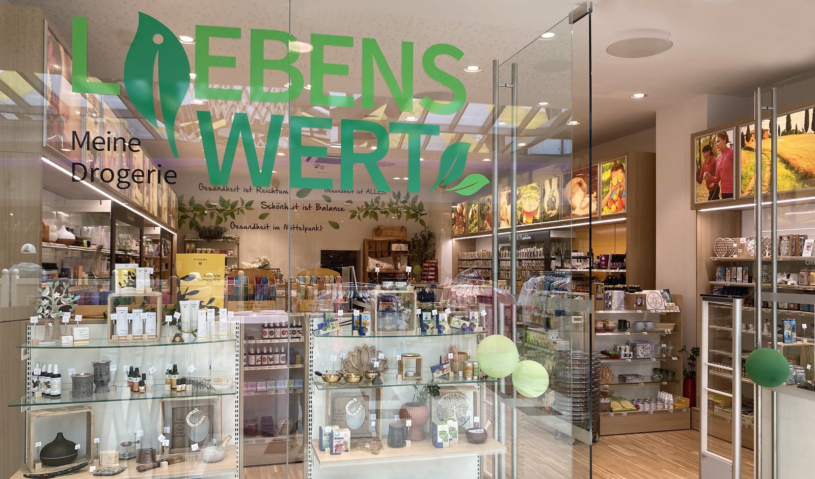 Eingang der Drogerie Liebenswert in der Passage Leobersdorf: grünes Logo „Liebenswert – Meine Drogerie“ auf der Glasfront, dahinter der helle Verkaufsraum mit Regalen